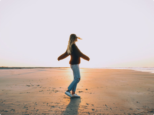 A woman playing in the beach as the sun sets